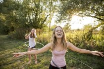 Two young girls in rural environment, fooling around, using hula hoops, — Stock Photo