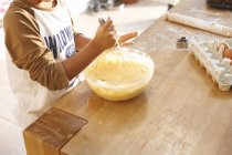 Boy beating mixture in bowl in kitchen — Stock Photo