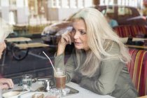 Mother and daughter sitting together in cafe, seen through cafe window — Stock Photo