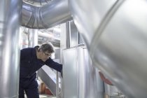 Инженер, осматривающий промышленные трубопроводы на электростанции — стоковое фото