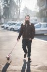 Junger bärtiger Mann spaziert mit Hund auf Straße — Stockfoto
