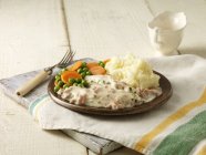 Plate of chicken breast fillets in cheese and bacon sauce with peas, carrots and mashed potatoes — Stock Photo