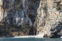 Barca ormeggiata in acqua da grotta in falesia — Foto stock