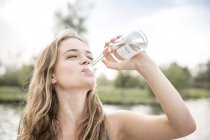 Молодая женщина пьет воду из бутылки, на открытом воздухе — стоковое фото