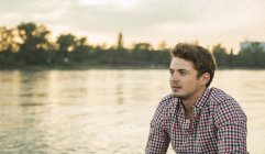 Молодой человек в клетчатой рубашке у озера — стоковое фото
