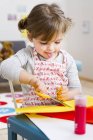 Дівчина ріже кольорову листівку вдома — стокове фото