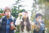 Siblings blowing bubbles in garden at home — Stock Photo