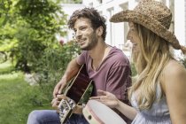Young man playing guitar, woman with tambourine — Stock Photo