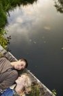 Visão aérea do jovem casal deitado na ponte de pedestres do rio — Fotografia de Stock