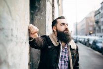Jovem barbudo homem por parede de concreto — Fotografia de Stock