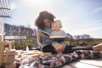 Mother reading book to son on picnic blanket — Stock Photo