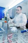 Лаборатория онкологических исследований, ученые, раздающие клетки с электронными пипетками — стоковое фото
