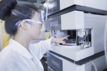 Young female scientist  removing sample from equipment in lab — Stock Photo