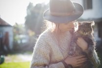 Jovem mulher usando chapéu, segurando gato — Fotografia de Stock