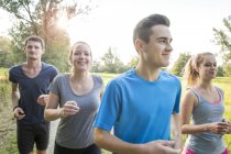Group of friends running through field — Stock Photo