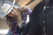 Young woman horseback rider in indoor paddock — Stock Photo