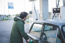 Homme utilisant la pompe à carburant pour voiture vintage dans la station-service de gaz — Photo de stock