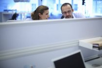 Empresario y empresaria charlando en escritorios en la oficina - foto de stock