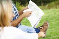 Couple putting on walking shoe, map reading and preparing for hiking — Stock Photo