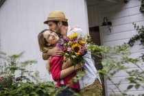 Jovem casal com um monte de flores abraçando no jardim — Fotografia de Stock