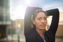 Portrait of young woman stretching, arms behind head — Stock Photo