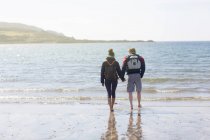 Casal adulto médio de mãos dadas na praia, Loch Eishort, Ilha de Skye, Hébridas, Escócia — Fotografia de Stock