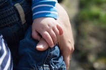 Niño sosteniendo el pulgar de la madre, concéntrate en las manos - foto de stock