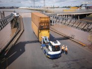 Elevated view of shipping containers and truck on ramp to ship — Stock Photo