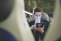 Ritratto di giovane uomo d'affari pendolare con tablet digitale in treno . — Foto stock