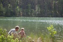 Father and son looking down into lake water, Somerniemi, Finland — Stock Photo
