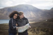 Mid adult couple in mountains with map — Stock Photo