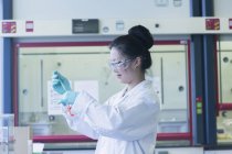 Científica femenina en muestra de pipeteo de laboratorio en vaso de precipitados de laboratorio - foto de stock
