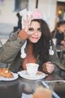 Портрет молодой женщины, делающей нормальный жест рукой в кафе на тротуаре — стоковое фото