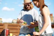 Couple eating and talking at rooftop party — Stock Photo