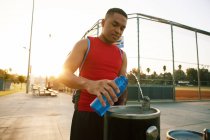 Junger Mann füllt Wasserflasche aus Trinkbrunnen — Stockfoto