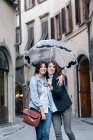 Lesbian couple standing together in street holding umbrella looking at camera smiling, Florence, Tuscany, Italy — Stock Photo