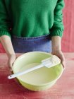 Immagine ritagliata di donna in grembiule che tiene ciotola con pasta in cucina — Foto stock