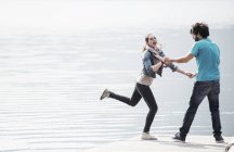 Jeune couple jouant sur la jetée du lac Mergozzo, Verbania, Piémont, Italie — Photo de stock