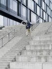 Ciclista urbano que lleva bicicleta escalera ascendente - foto de stock