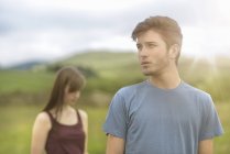 Adolescente casal de pé à parte e olhando para longe na paisagem rural sob céu ensolarado brilhante — Fotografia de Stock