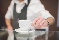 Обрезанное изображение баристы, подающей кофе через прилавок — стоковое фото