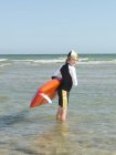 Retrato del niño nieto (niños salvavidas surfeando) mirando hacia atrás, Altona, Melbourne, Australia - foto de stock