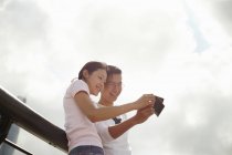 Низкий угол зрения туристической пары, глядя на мгновенные фотографии фильма, Бунд, Шанхай, Китай — стоковое фото