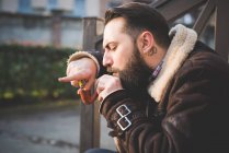 Junger bärtiger Mann raucht Pfeife auf Stufen — Stockfoto
