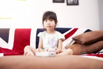 Junges Mädchen sitzt auf dem Sofa und schaut zu Hause fern — Stockfoto