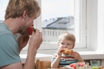 Father and toddler son eating breakfast at kitchen table — Stock Photo