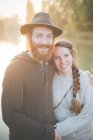 Young couple sitting by river, portrait — Stock Photo