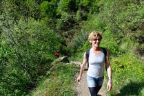 Femme mûre randonneur randonnée à flanc de colline — Photo de stock