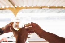 Tre mani maschili e femminili che fanno un brindisi con vino bianco — Foto stock