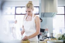 Жіночий шеф-кухар нарізає овочі на комерційній кухні — стокове фото